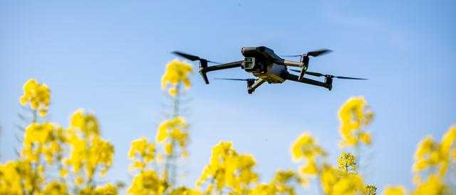 a drone with a camera flying over crops.