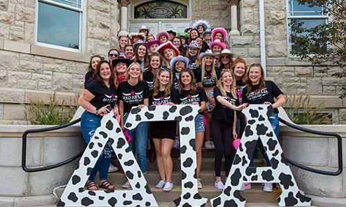 a group of sorority students standing in front of a building.	